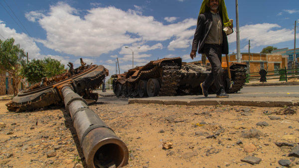 Greeting the deal, the UN said some 5.2 million people need humanitarian assistance in Tigray, including 3.8 million who need healthcare. Photograph shows a man passing a destroyed tank on the main street of Edaga Hamus in the Tigray region on 5 June 2021 (Yan Boechat/VOA/Public domain)